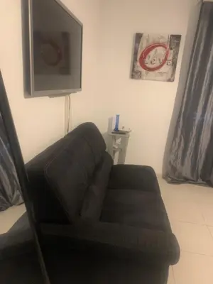 a black couch in a living room with a tv at Trés Bel appartement de 105 M2 et 45 M2 de terrasse à 100 m du port in Porto-Vecchio