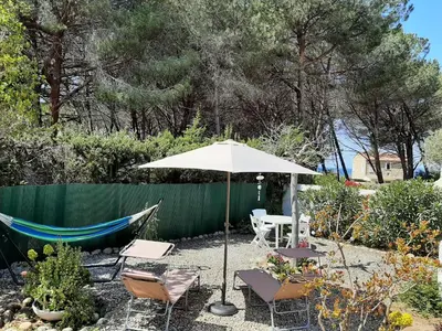 a patio with an umbrella and chairs and a hammock at Piccula Casa in Albitreccia