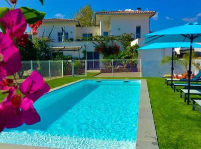 a swimming pool in front of a house with pink flowers at Les bougainvilliers in Penta-di-Casinca