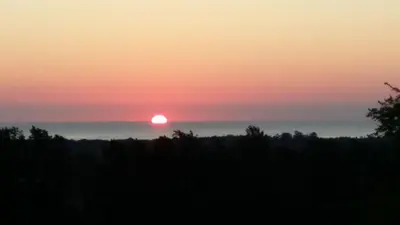 a sunset over a field with the sun in the horizon at Les bougainvilliers in Penta-di-Casinca