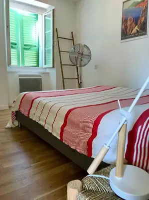 a bedroom with a bed with a red and white blanket at Charmant T3 Centre ville Corté in Corte