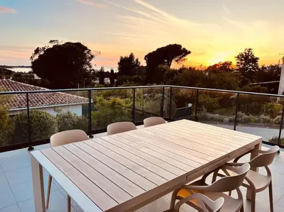 a table and chairs on a balcony with the sunset at Villa Livia Porticcio piscine 500m plage in Porticcio