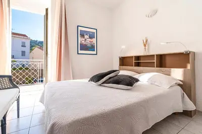 a bedroom with a bed with white sheets and a window at Alla Casa - Appt pour 6 avec terrasse in Aregno