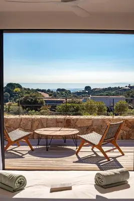 a patio with a table and chairs and a view of the ocean at VILLA ISULA BELLA in Porto-Vecchio