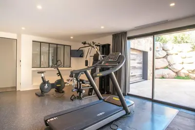 a gym with a treadmill and two exercise bikes at VILLA ISULA BELLA in Porto-Vecchio