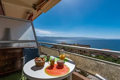 a table with a plate of food on a balcony at Chapelle des Grecs - 1km de la plage in Ajaccio