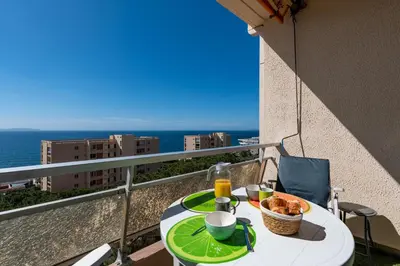 a table with a plate of food on a balcony at Chapelle des Grecs - 1km de la plage in Ajaccio