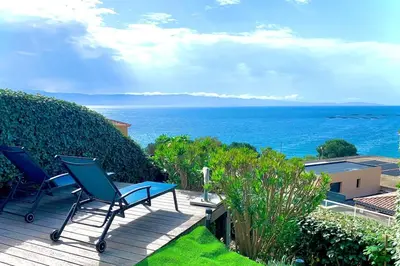 a patio with chairs and the ocean in the background at Ajaccio maison bord de mer dans résidence avec piscine in Ajaccio