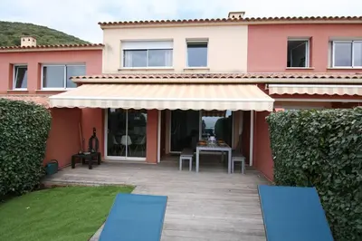 a house with a patio and two blue chairs at Ajaccio maison bord de mer dans résidence avec piscine in Ajaccio