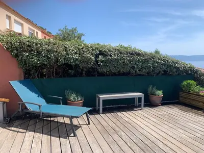 a blue bench and a table on a deck at Ajaccio maison bord de mer dans résidence avec piscine in Ajaccio