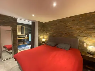 a bedroom with a red bed and a brick wall at Maison de caractère, Zilia, au pied du Montegrossu in Zilia