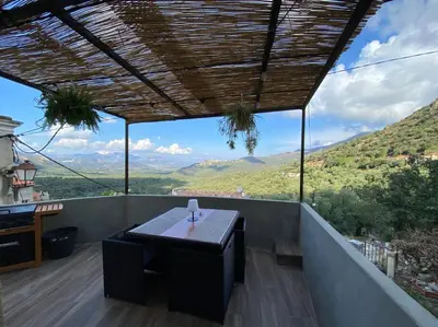 a table on a balcony with a view of mountains at Maison de caractère, Zilia, au pied du Montegrossu in Zilia