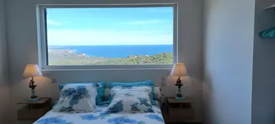 a bedroom with a large window above a bed at U CASEDDU- Villa piscine privée chauffée- vue mer- clim-wifi in Sari Solenzara