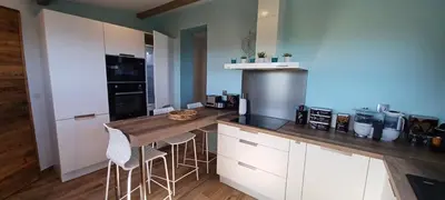 a kitchen with white cabinets and a counter with stools at U CASEDDU- Villa piscine privée chauffée- vue mer- clim-wifi in Sari Solenzara