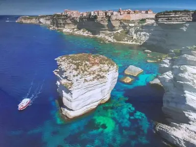 a large rock in the water with a boat in it at T2 d'exception 100m plage terrasse vue mer et montagnes in Propriano