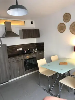 a kitchen with a table and chairs and a stove at T2 récent climatisé à 100m du port in Propriano