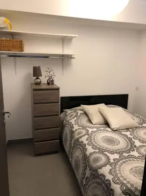a bedroom with a bed and a dresser with a lamp at T2 récent climatisé à 100m du port in Propriano