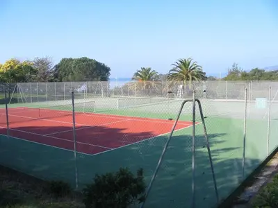 a tennis court with a net on a tennis court at Maison Les couchants Porticcio in Porticcio