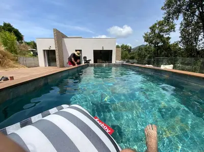 a person laying on a chair in a swimming pool at Villa d'Architecte Casa Mado avec Piscine vue imprenable in Ajaccio