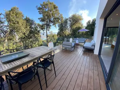 a wooden deck with a table and chairs on it at Villa d'Architecte Casa Mado avec Piscine vue imprenable in Ajaccio