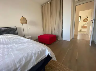 a bedroom with a bed and a red ottoman at Villa d'Architecte Casa Mado avec Piscine vue imprenable in Ajaccio