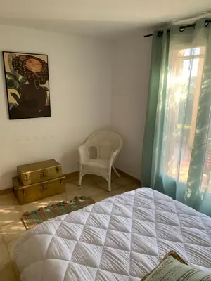 a bedroom with a bed and a chair and a window at VILLA Bord de Mer in Cervione