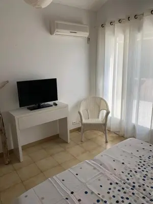 a bedroom with a bed and a tv and a chair at VILLA Bord de Mer in Cervione