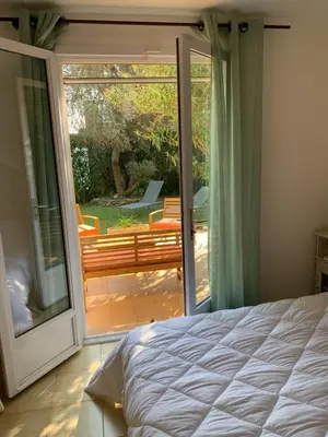 a bedroom with a bed and a sliding glass door at VILLA Bord de Mer in Cervione