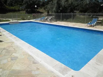 a large blue swimming pool with two lounge chairs at Résidence Kallisté in Sollacaro