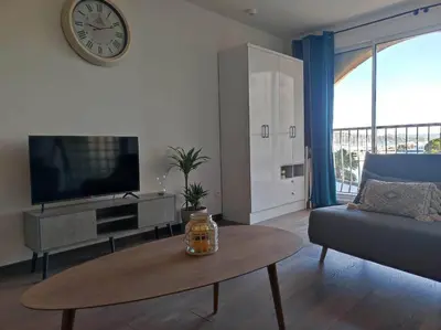 a living room with a couch and a table and a clock at Appartement sur le port Résidence Marina Palmu in Porto-Vecchio