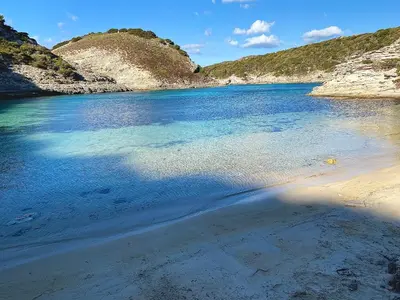 a body of water with a sandy beach and mountains at Chez François et Cécile in Figari