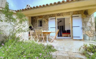 a stone house with a table and chairs on a patio at Les bergeries d'Ogliastrello in Figari