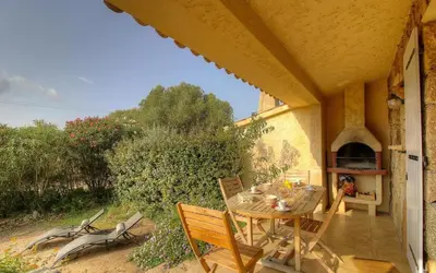 a table and chairs on a patio with a fireplace at Les bergeries d'Ogliastrello in Figari