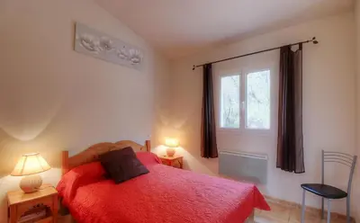 a bedroom with a red bed and a window at Les bergeries d'Ogliastrello in Figari