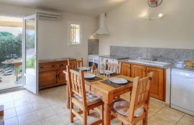 a kitchen with a wooden table and chairs and a counter at Les bergeries d'Ogliastrello in Figari