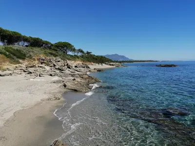 a beach with rocks and the ocean on a clear day at La Caletta Corsa Apartments - 2 Camere con Terrazza Privata, Aria Condizionata, 100m dal Mare in Linguizzetta