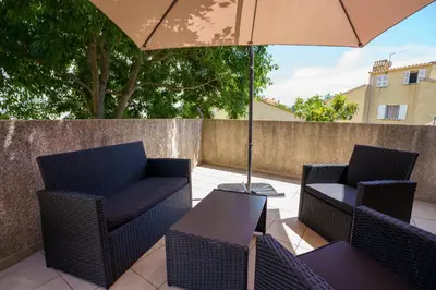 a patio with two chairs and a table with an umbrella at La Caletta Corsa Apartments - 2 Camere con Terrazza Privata, Aria Condizionata, 100m dal Mare in Linguizzetta