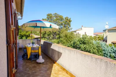 a table with an umbrella on a balcony at La Caletta Corsa Apartments - 2 Camere con Terrazza Privata, Aria Condizionata, 100m dal Mare in Linguizzetta