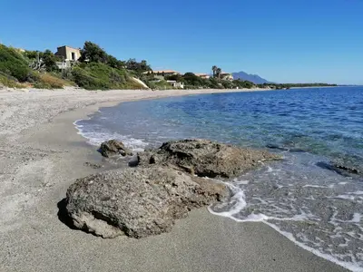 a beach with rocks in the sand and water at La Caletta Corsa Apartments - 2 Camere con Terrazza Privata, Aria Condizionata, 100m dal Mare in Linguizzetta