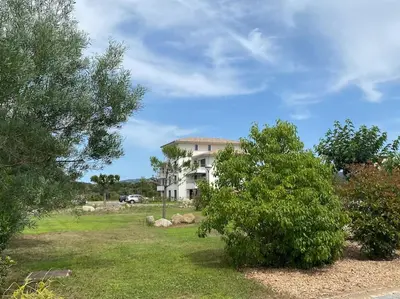 a house in the middle of a yard with trees at T2 neuf 4 personnes avec piscine/terrain tennis in Porto-Vecchio