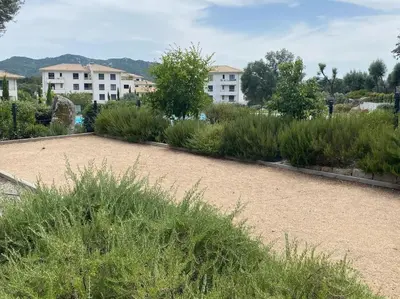 a garden with tall grass and buildings in the background at T2 neuf 4 personnes avec piscine/terrain tennis in Porto-Vecchio