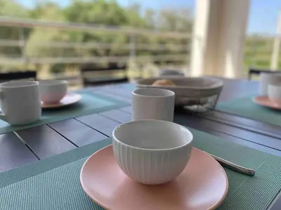 a table with bowls and plates on a table at T2 neuf 4 personnes avec piscine/terrain tennis in Porto-Vecchio
