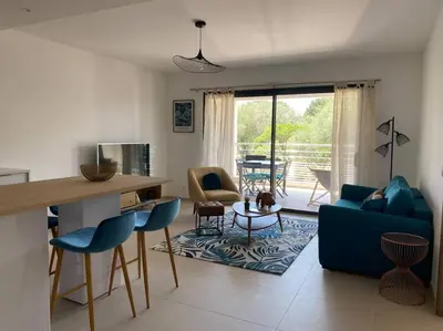 a living room with a blue couch and a table at T2 neuf 4 personnes avec piscine/terrain tennis in Porto-Vecchio
