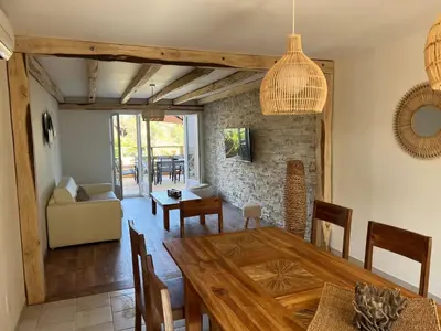 a dining room and living room with a wooden table at Luxueuse Villa, Hyper centre PORT de PORTO VECCHIO in Porto-Vecchio