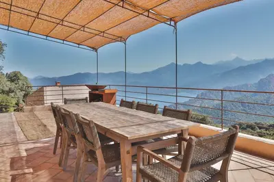 a wooden table and chairs on a balcony with a view at Les Demeures de Piana in Piana