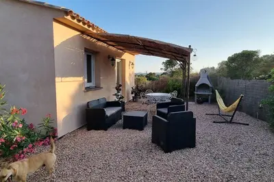 a dog standing in front of a patio with chairs and a hammock at Chez Baptiste et Laura in Figari