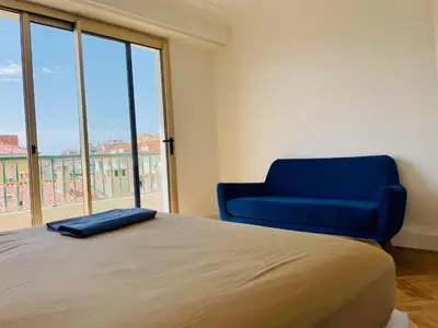 a bedroom with a bed and a blue chair at Spacieux 2 pièces Centre Historique Ajaccio in Ajaccio