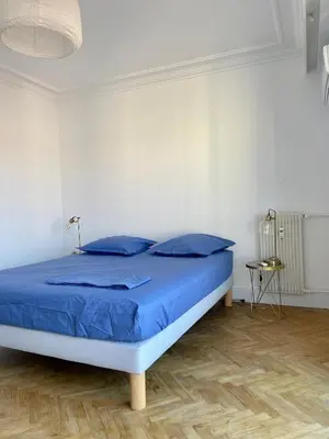 a bed in a white room with blue pillows at Spacieux 2 pièces Centre Historique Ajaccio in Ajaccio