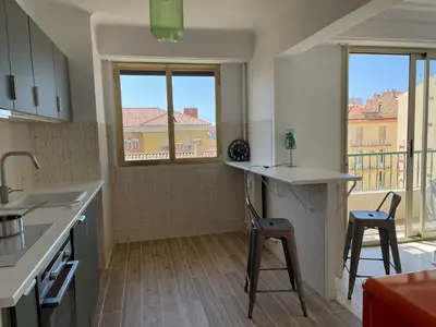 a kitchen with a counter and two stools in it at Spacieux 2 pièces Centre Historique Ajaccio in Ajaccio