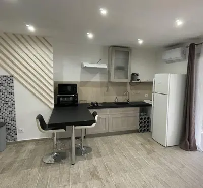 a kitchen with a black table and a refrigerator at U Secondu Appart neuf spacieux au calme in Aléria